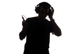 Silhouette,Of,Young,Man,With,A,Smartphone,Listening,To,Music