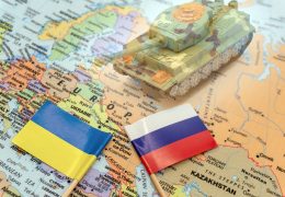 Ukrainian and Russian flags placed on a map of Europe. Ukraine crisis and Conflict. Double exposure image of blurred tank.Choose to focus on the flags. International situation theme